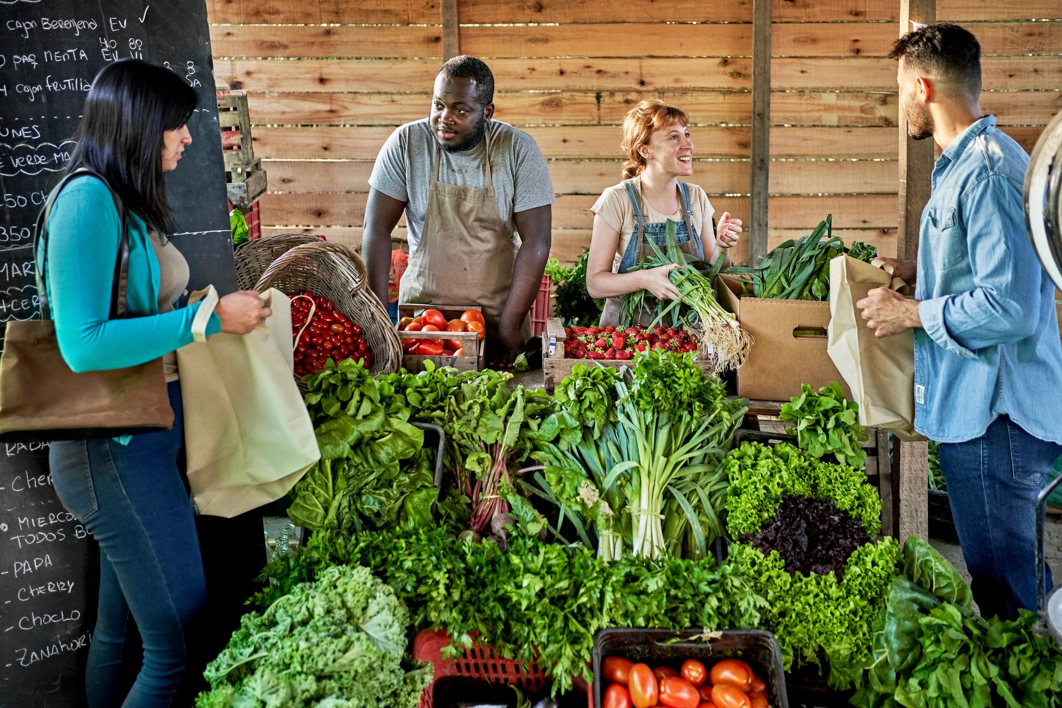 Customers selecting vegetables at a farmers market stand